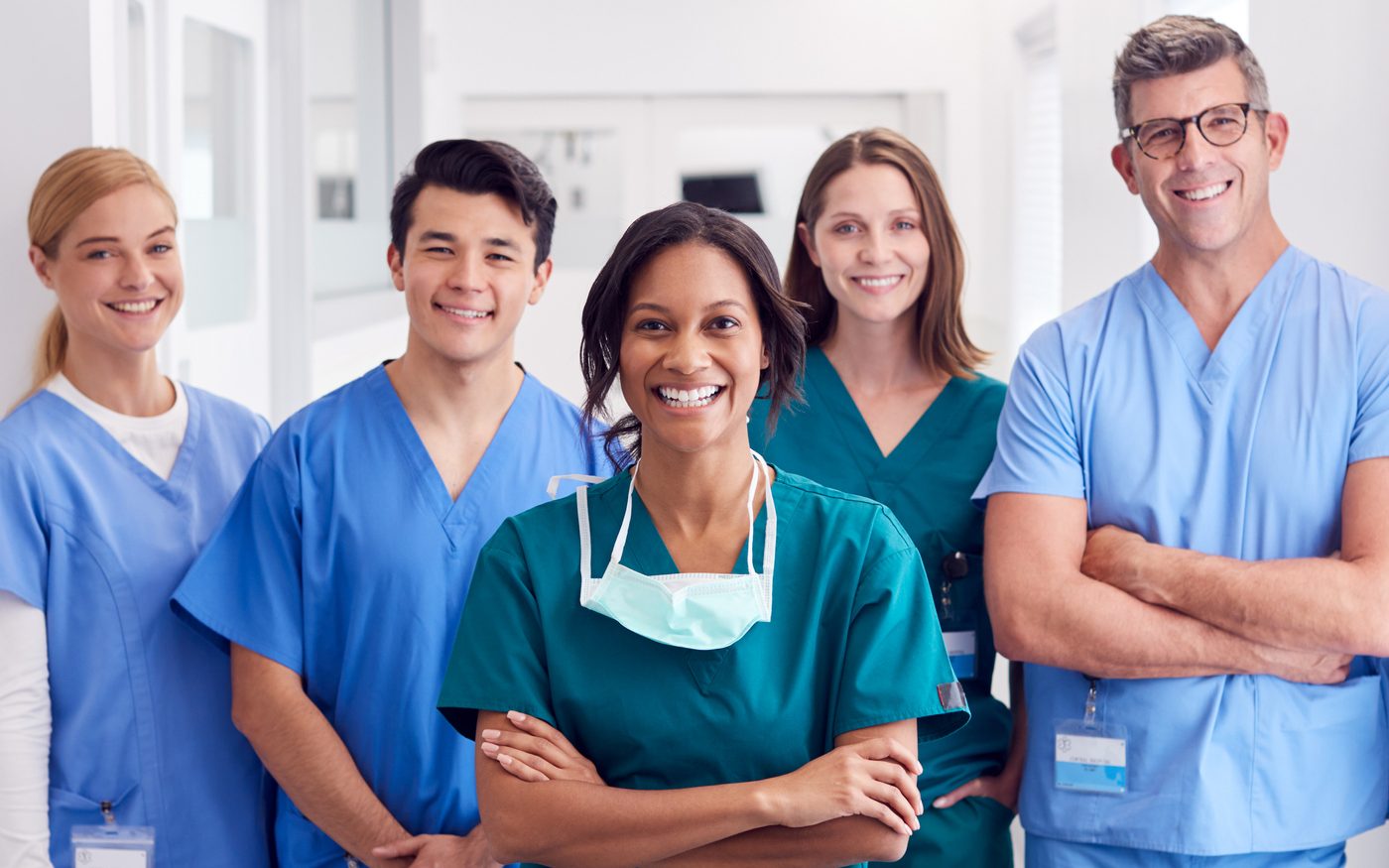 Portrait Of Smiling Multi-Cultural Medical Team Standing In Hospital Corridor